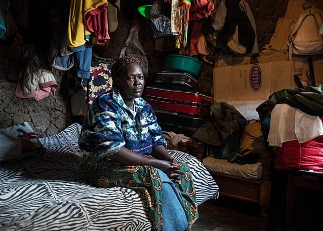 The room where Peter's parents sleep; their worldly possessions are stacked in the little space there is around their bed and their clothes hang from the ceiling.