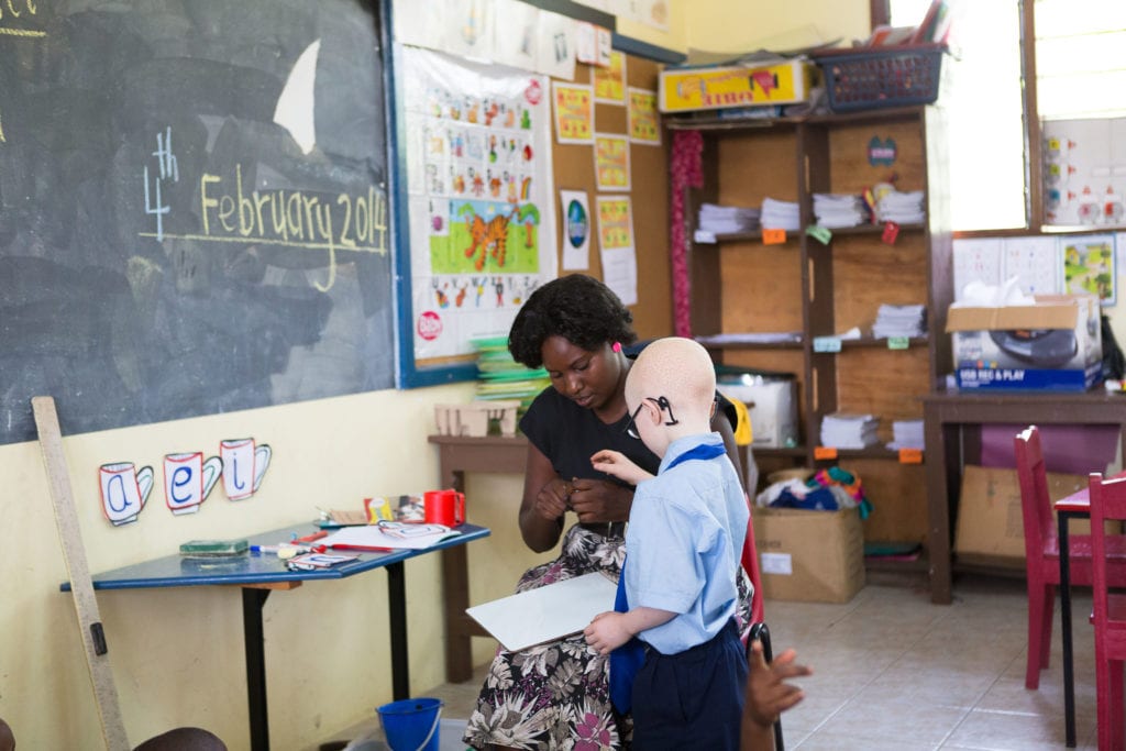 Lower Primary teacher Anna Nnko helping Sebastian in class