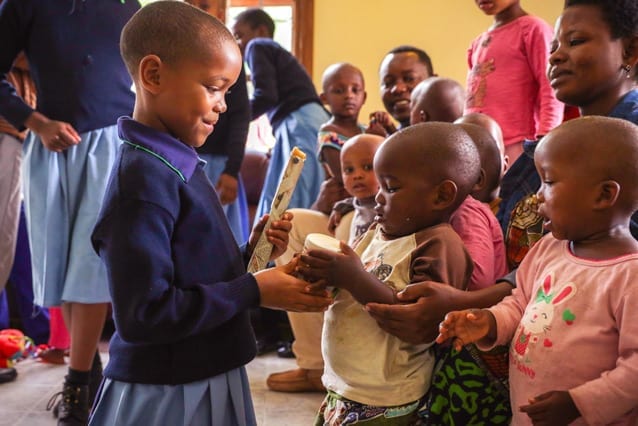 Helping hand: St Jude's primary school student Hawa gives a gift to one of the orphans at Neema House.