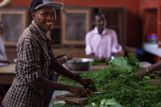 Super food: A secondary student shares a smile while shredding spinach.