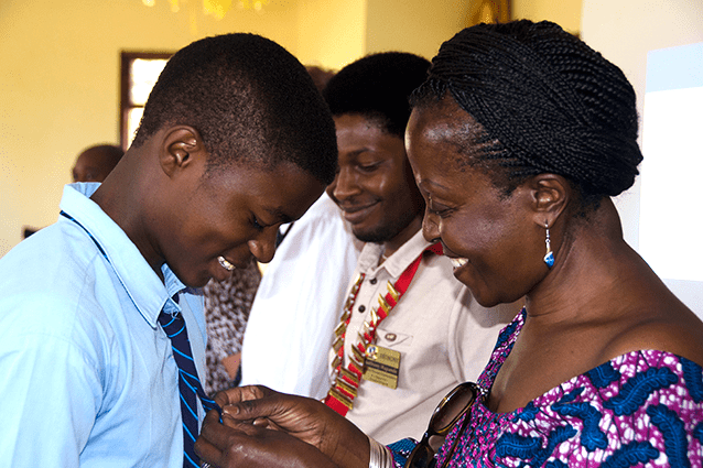 All smiles: Form 4 student Edgar appreciatively accepts a club pin from Arusha Mt Meru club President Anna Rweyemamu.