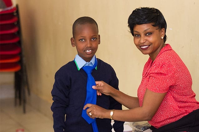 Tie-ing it together: Supporter Relations Coordinator, Joycelyn, helps a student with his new uniform. 