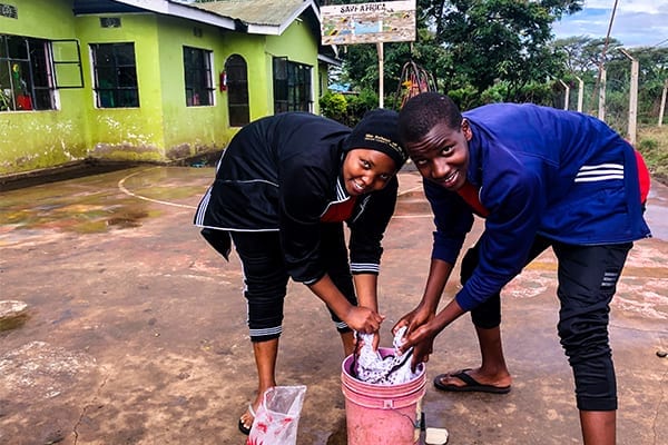 Helping Hand: Zuhura & Deogratius wash clothes at the orphange.