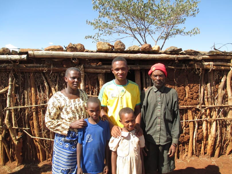 Family standing in front of hut