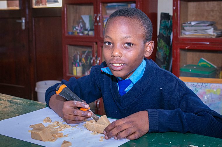 Standard 5 student carves a boat during an art class.